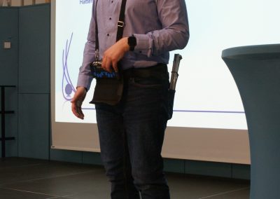 Mag. Thomas Hill hält den ersten Vortrag des Tages. Er steht auf der Bühne, hinter ihm ist seine Präsentation zu sehen.