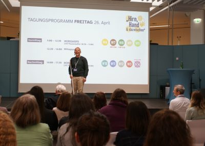 Juan Ruiz auf der Bühne. Er erzählt eine humorvolle Anekdote aus seiner Kindheit.