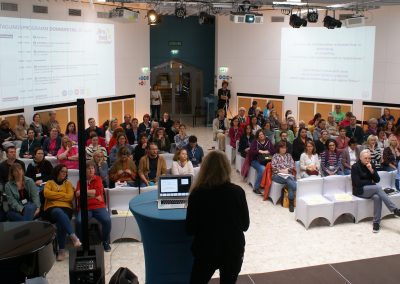Vortrag von Frau Brencic mit Blick in das Auditorium. Die Aula des BBI ist gut gefüllt.
