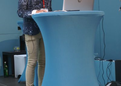 Clemens Engelhart hält den vierten und letzten Vortrag des Tages. Er steht am Rednerpult und spricht mit den Teilnehmer*innen.