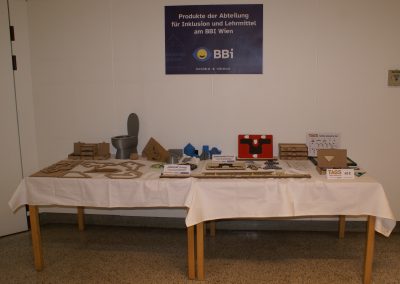 Tisch mit Produkten der Abteilung für Inklusion und Lehrmittel. Tagungsteilnehmer*innen können die Produkte näher betrachten und ausprobieren.